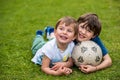 Two smiling kids laying on the grass holding a soccer ball Royalty Free Stock Photo