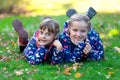 Two smiling kids siblings girls having fun in autumn park