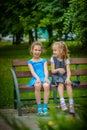 Two smiling little sisters sit on bench