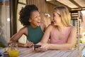 Two Smiling Multi-Cultural Female Friends Outdoors At Home Looking At Mobile Phone Royalty Free Stock Photo