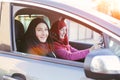 Two smiling muslim women inside a car