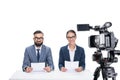 two smiling newscasters with papers sitting in front of camera, Royalty Free Stock Photo