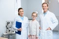 two smiling ophthalmologists and little child