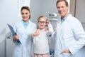 two smiling optometrists and little kid in eyeglasses showing