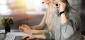 Two smiling people in headsets are talking to the clients, while sitting at the desk in sunny modern office Royalty Free Stock Photo