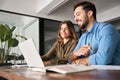 Two smiling professional business people talking using laptop working in office. Royalty Free Stock Photo