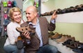 Two retirees together choosing pair of shoes for men in shoe store Royalty Free Stock Photo