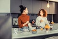 Happy girls cooking breakfast together in the kitchen