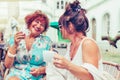 Two smiling senior women talking and drinking coffee while looking each other in a outdoor cafe Royalty Free Stock Photo