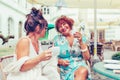 Two smiling senior women talking and drinking coffee  in a outdoor cafe Royalty Free Stock Photo