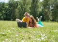 Two smiling teenagers students with laptop resting on meadow. Education. Technology. Royalty Free Stock Photo