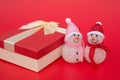 Two smiling toy christmas snowman and a present box on red Royalty Free Stock Photo