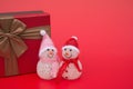 Two smiling toy christmas snowman and a present box on red background Royalty Free Stock Photo