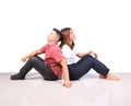 Two smiling woman young girls and happiness tomboy friends sitting back to back on tile floor in home with white background Royalty Free Stock Photo