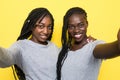 Two smiling young african girls taking a selfie isolated over yellow background Royalty Free Stock Photo