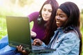 Two smiling young girls using laptop at the park Royalty Free Stock Photo