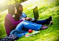 Two smiling young girls using laptop at the park Royalty Free Stock Photo