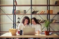 Two smiling young woman working at a laptop