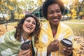 Young women friends chatting outdoors and drinking coffee while enjoying the walk in the park together Royalty Free Stock Photo