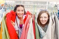 Smiling young women friends shopping for summer clothes together at outdoor flea market