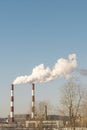 Two smoking chimneys against the blue sky. Ecological problems. Royalty Free Stock Photo