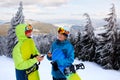 Two snowboarders talking and holding smartphones. Friends looking at cellphone and communicating in social network Royalty Free Stock Photo