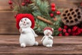 Two snowman figurines in red hats, white snowflakes on a dark wooden textured background. Christmas toys Royalty Free Stock Photo