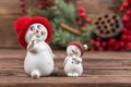 Two snowman figurines in red hats, white snowflakes on a dark wooden textured background. Christmas toys Royalty Free Stock Photo