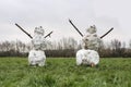 Two snowman standing on a green grass in a park Royalty Free Stock Photo