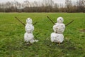 Two snowman standing on a green grass in a park Royalty Free Stock Photo