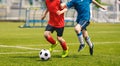 Two soccer players chase a soccer ball in a duel. Boys play soccer match on the grass pitch Royalty Free Stock Photo