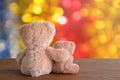 Two soft toys bears are sitting on brown wooden background. Blurred bokeh background