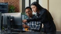 Two software developers coming at desk and sitting down holding laptop with coding interface Royalty Free Stock Photo