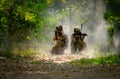 Two soldiers with the fighting uniform sit on the ground and point gun to target for the concept war battle in jungle