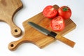 Two solid oak wooden cutting boards, a chopped fresh red tomato and a sharp knife on a white background. The concept of preparing Royalty Free Stock Photo