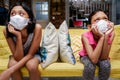 Two Asian Little Girls Wearing Medical Face Mask Getting Bored Sitting on Sofa Apart from Each Other