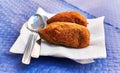 Two spanish croquettes on paper surface