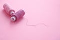 Two spools of sewing thread lilac pink, violet, crimson on a pink paper backgroun. Royalty Free Stock Photo