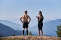 Two sports people admiring mountain landscape from top of one hill. Royalty Free Stock Photo