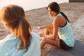 Two sports women friends outdoors on the beach sitting talking with each other Royalty Free Stock Photo