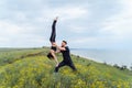 Two sportsmen practicing acro yoga together outdoors in the evening. Balancing girl legs up. Perfect flexibility. Athlete standing
