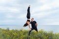 Two sportsmen practicing acro yoga together outdoors in the evening. Balancing girl legs up. Perfect flexibility. Athlete standing