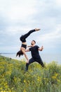 Two sportsmen practicing acro yoga together outdoors in the evening. Balancing girl legs up. Perfect flexibility. Athlete standing