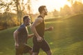 The two sportsmen running on the grass on the sunny background.