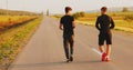 The two sportsmen running on the street on the sunny background.