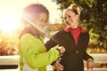 Two sportswomen in park, smiling and looking at watch.