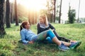 Two sporty girlfriends relaxing, lying on grass and chatting in the forest after jogging together Royalty Free Stock Photo