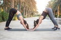 Two sporty young women doing yoga exercises together in the park. Fit girls in roof pose on exercise mat outdoors. Royalty Free Stock Photo