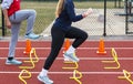 Two sprinter runners performing form drills over yellow banana hurdles