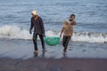 Two Sri Lankan fishermen carry a basket with caught fish